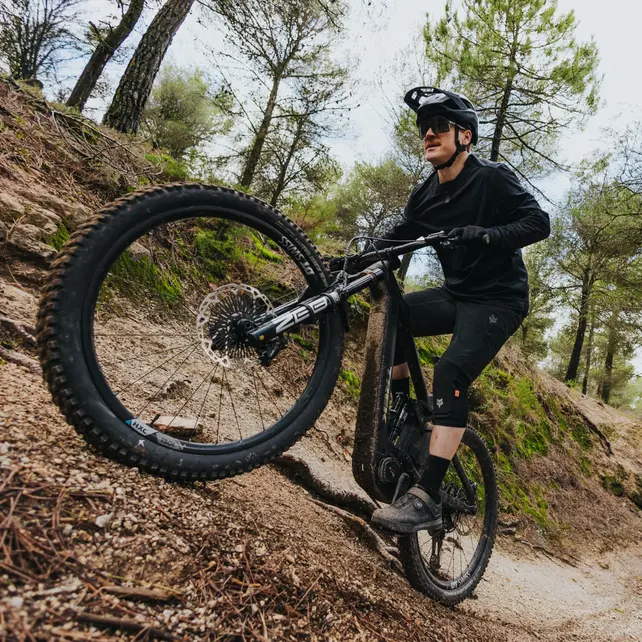 E-Mountainbike im Gelände: Mountainbiker fährt mit einem leistungsstarken E-Bike einen steilen Waldtrail bergauf und meistert anspruchsvolle Offroad-Passagen.