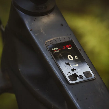 Nahaufnahme des Bosch Kiox 400C integrierten E-Bike-Displays im Rahmen, zeigt Fahrdaten wie Geschwindigkeit, Akkustand und Fahrmodus ‚Race‘ auf einem Mountainbike im Gelände