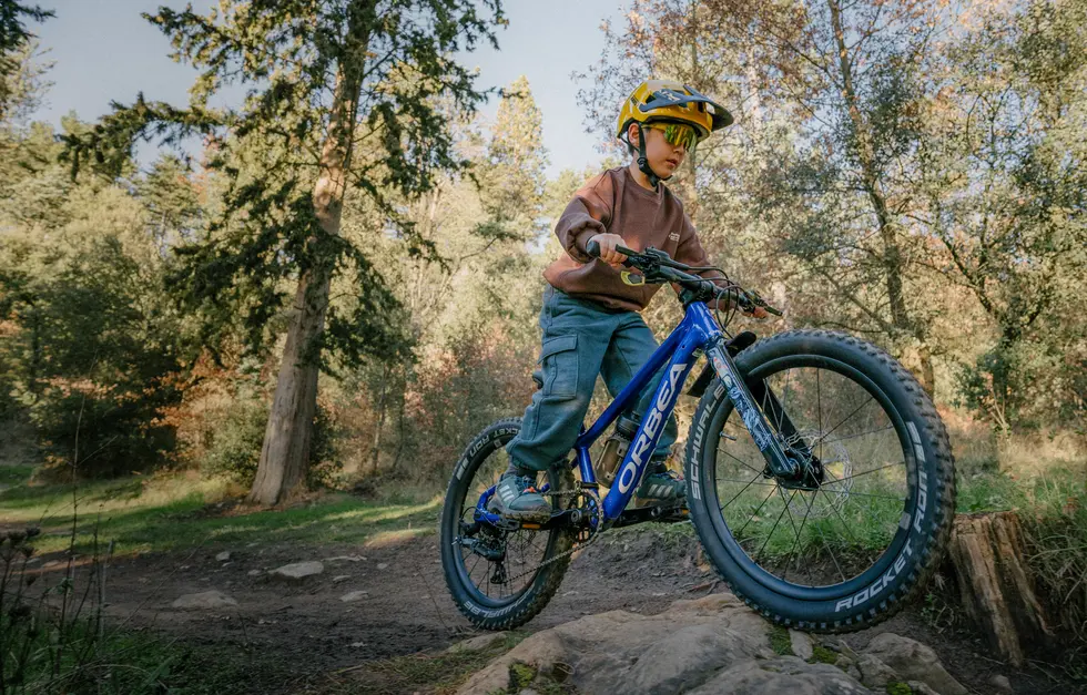 Orbea Kimu 20 Kinderfahrrad. Das Kindermountainbike überzeugt durch leichtes Gewicht. Für Kinder von 5 bis 8 Jahren.
Im Bild fährt ein Junge mit dem Orbea Kimu 20 auf einem Mountainbike Trail über einen Stein.