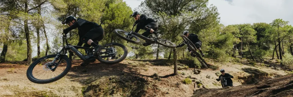 Mountainbiker mit modernem Bosch E-Bike Antriebssystem springt dynamisch über einen Trail im Wald – Symbolbild für die neuesten Bosch E-Bike Innovationen, Performance Line Motoren und verbesserte Fahrtechnik im Gelände