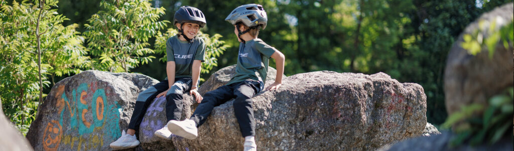 Kinder mit Fahrradhelmen und Fahrrädern beim sicheren Radfahren in der Natur.