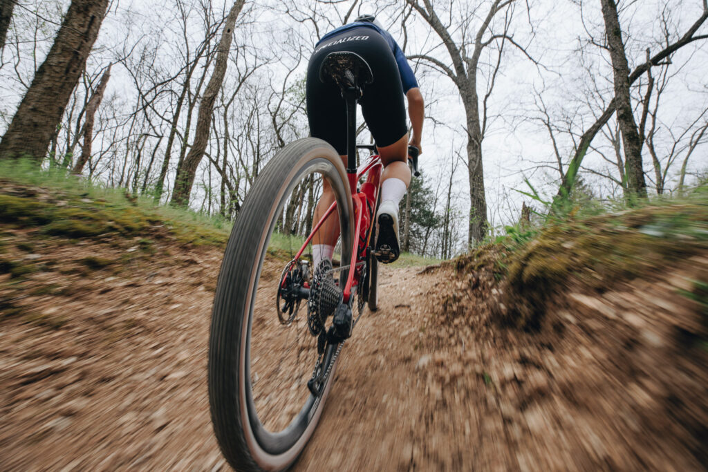 Gravel-Bike Fahrradreifen sind Reifen die deutlich breiter als Rennradreifen sind und auf Schotter, Straßen und schlechten asphaltieren Wegen zuhause sind. In dem Bild sieht man einen Gravel-Bike Fahrer der auf einen Schotterweg mit dem Gravel-Bike fährt.