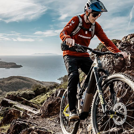 E-Mountainbike im Gelände: Mountainbiker fährt mit einem leistungsstarken E-Bike einen steilen Waldtrail bergauf und meistert anspruchsvolle Offroad-Passagen.