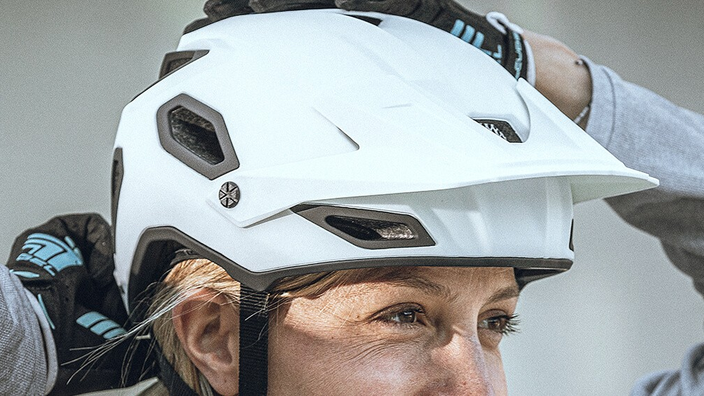 Person setzt einen modernen Mountainbike-Helm richtig auf – die korrekte Anpassung des Fahrradhelms sorgt für optimalen Schutz und sicheren Sitz beim Radfahren