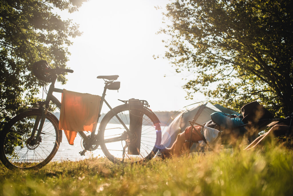 Camping am See mit Zelt und Tourenrad bei sonnigem Gegenlicht