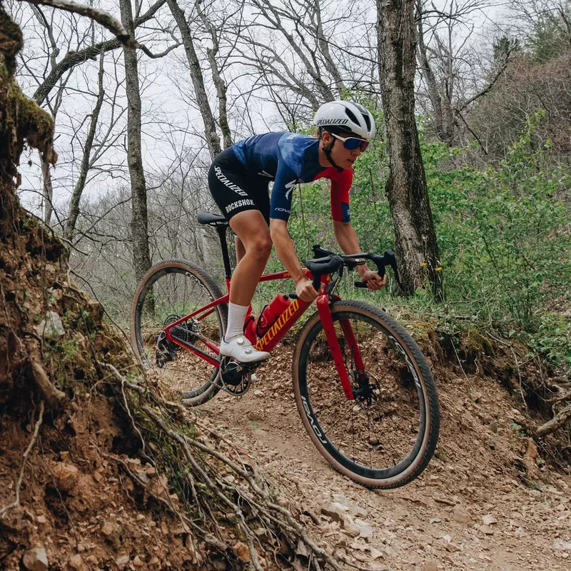 Gravel-Bike. Im Bild sieht man einen Mann der mit einem roten Specialized Gravel-Bike einen Weg fährt. 
Der Unterschied zwischen Gravel-Bike und Rennrad erklärt